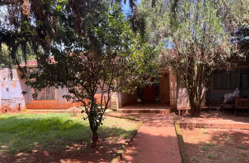 Antes: vivienda existente de ladrillo visto con jardín de árboles maduros